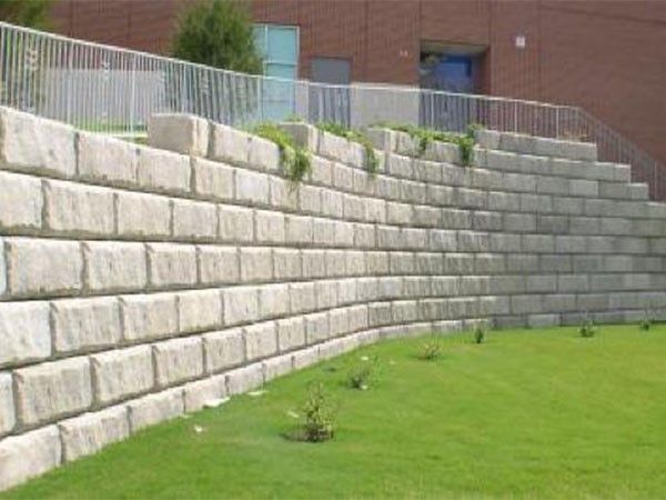 Tiered concrete block retaining wall built along a landscaped lawn with multiple levels for soil support during a concrete block retaining wall service in Heber City, UT
