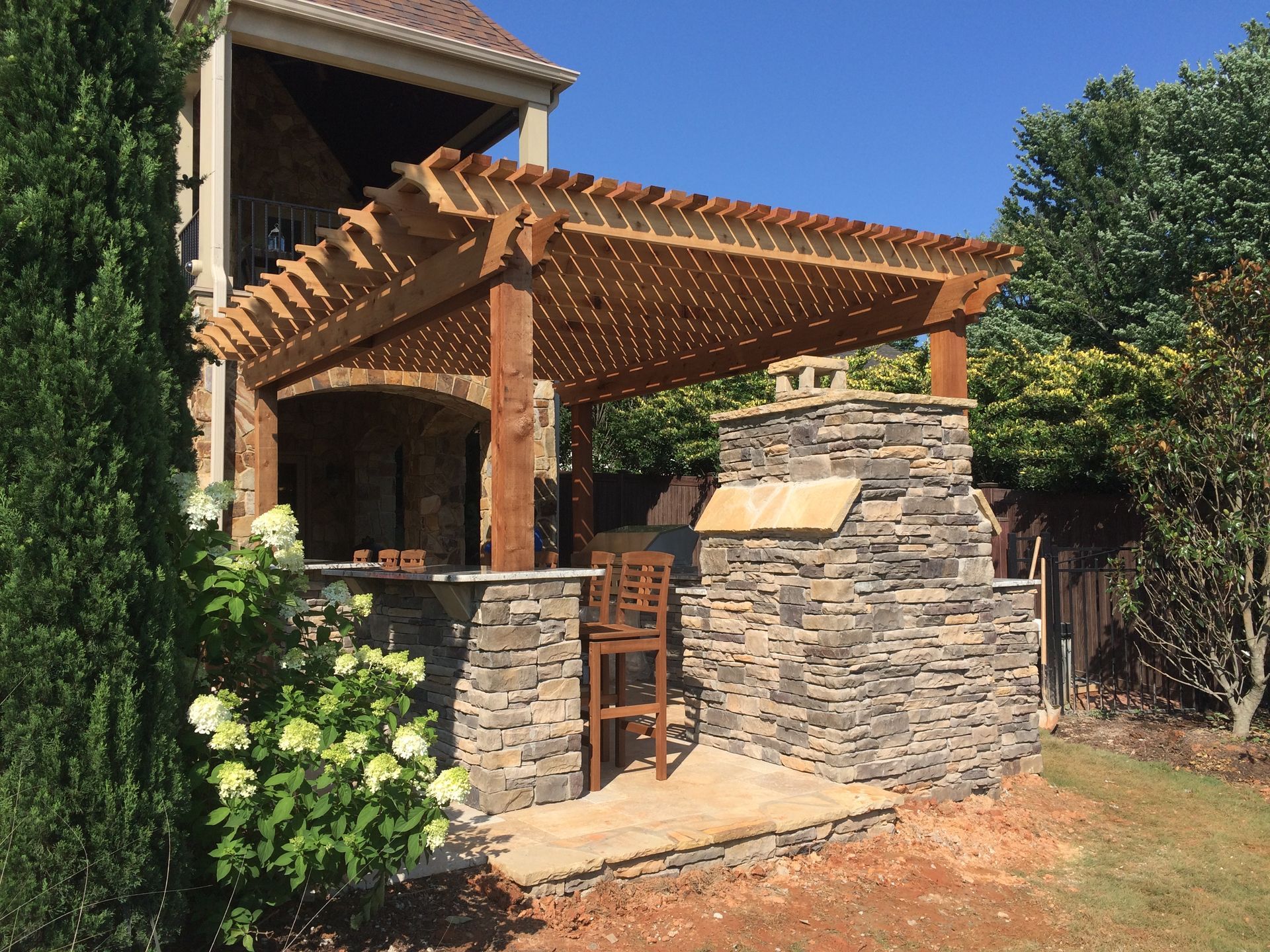 a wooden pergola is sitting on top of a patio next to a house .