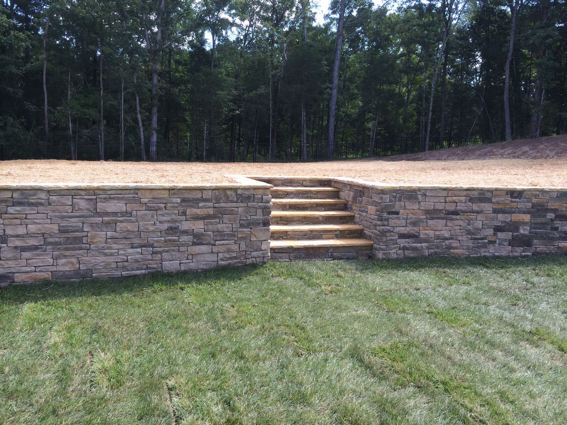 a stone wall with stairs leading up to it in a garden 