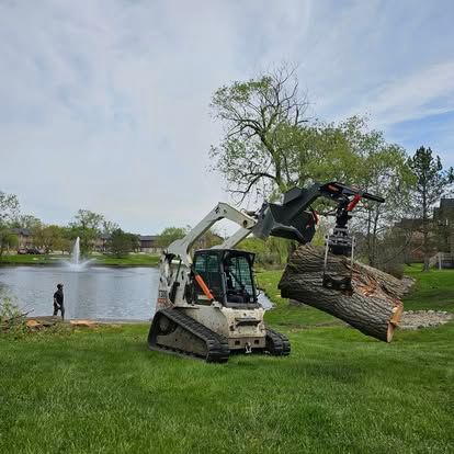 A worker in a blue cap feeds tree branches into a large yellow wood chipper on a suburban street.