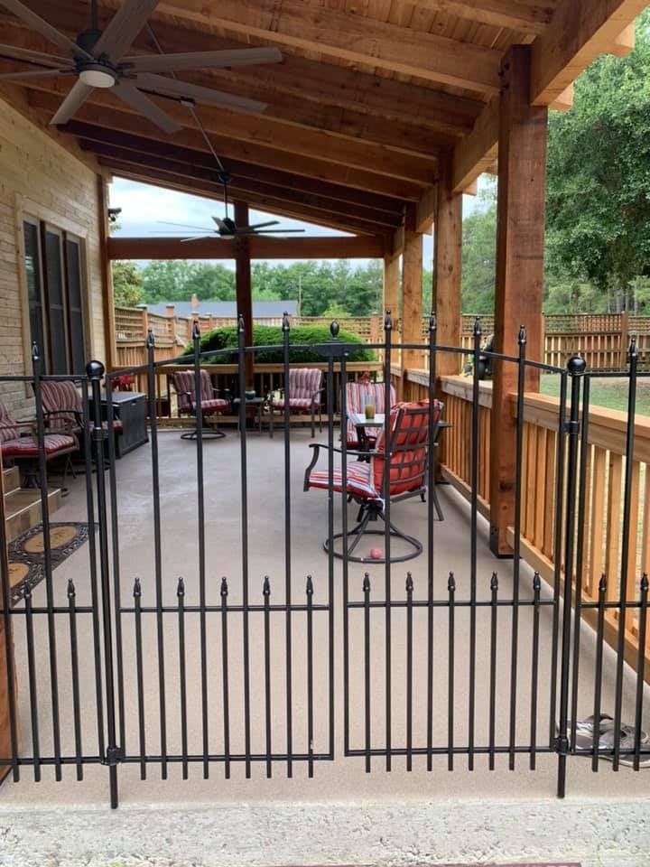 Black wrought-iron gate opens onto a covered patio with seating and a wooden ceiling.