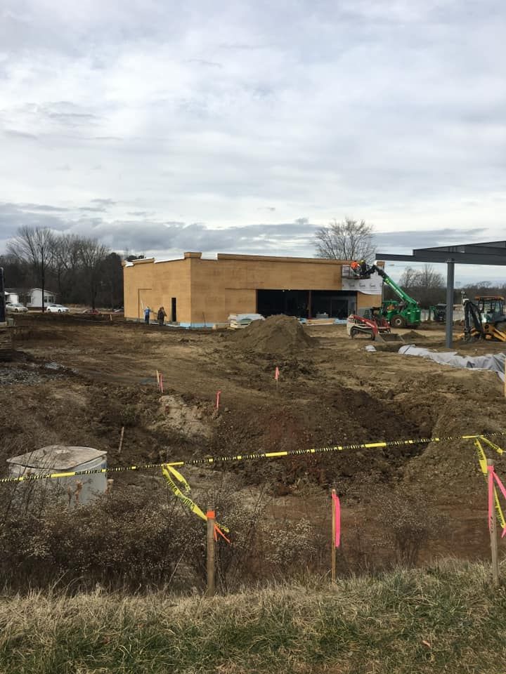 Construction site with a partially built building, green crane, and excavated ground.