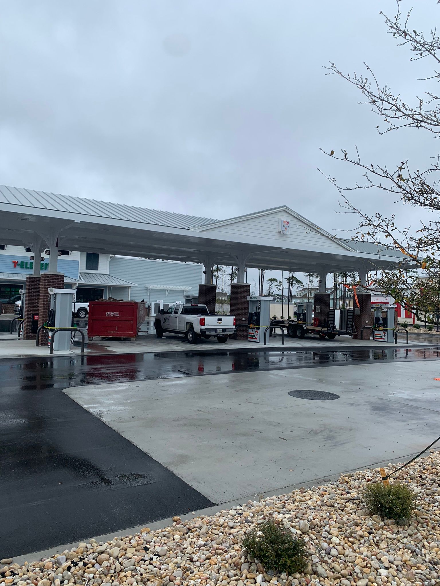 Gas station exterior under a cloudy sky; trucks and equipment present.