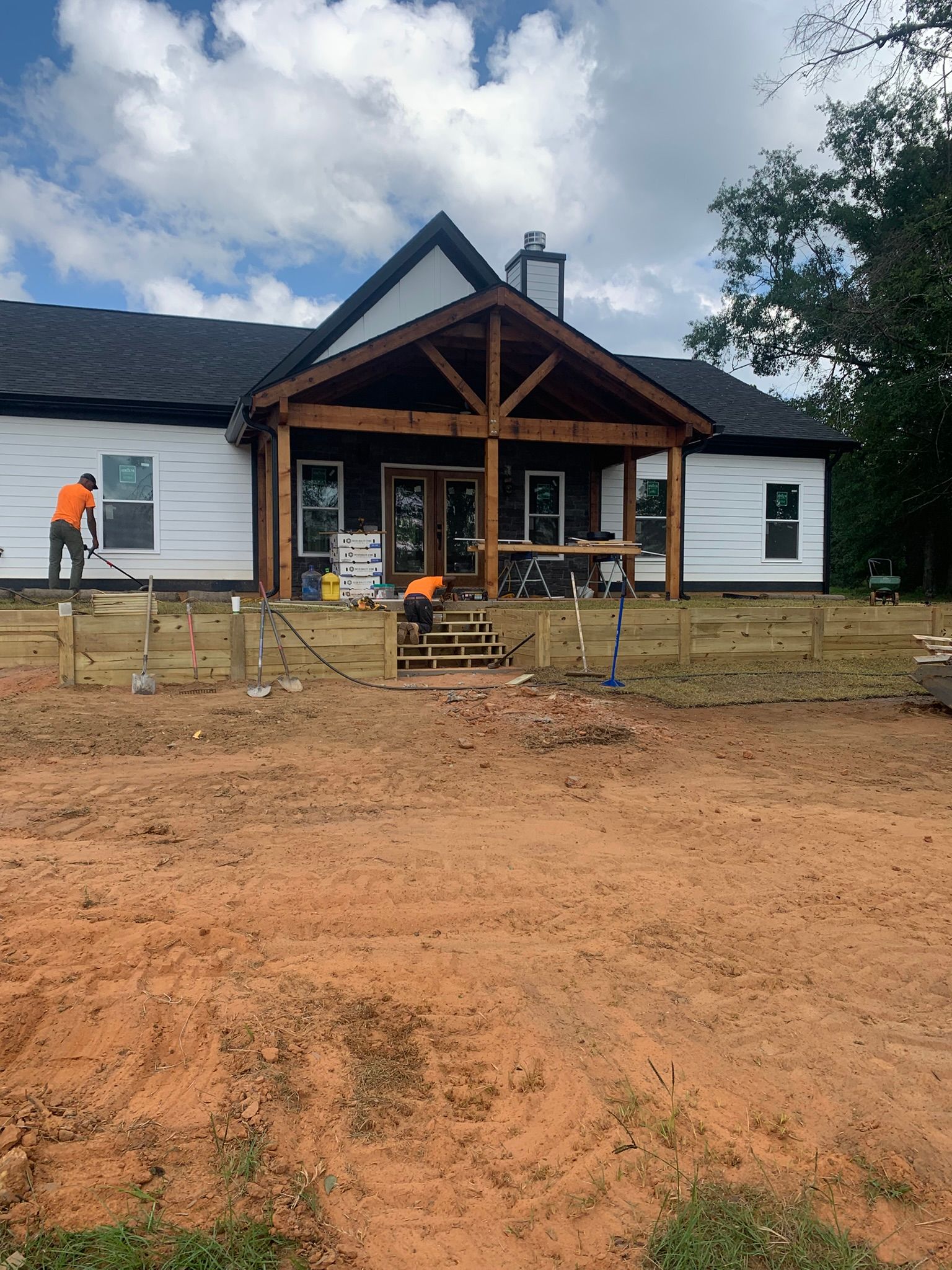 Construction workers building a wooden porch on a white house.