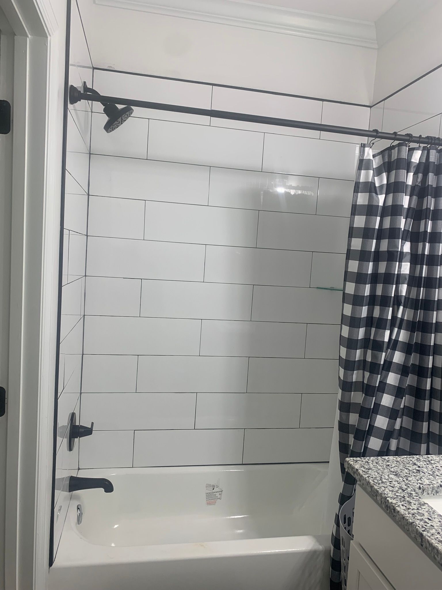 Black and white bathroom with subway tile, shower curtain, and fixtures.