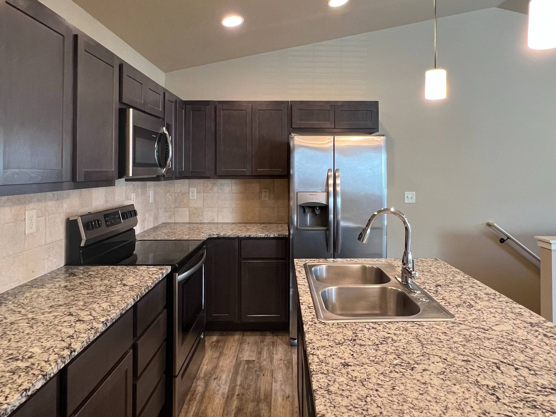 Kitchen with dark cabinets, stainless steel appliances, and granite countertops.