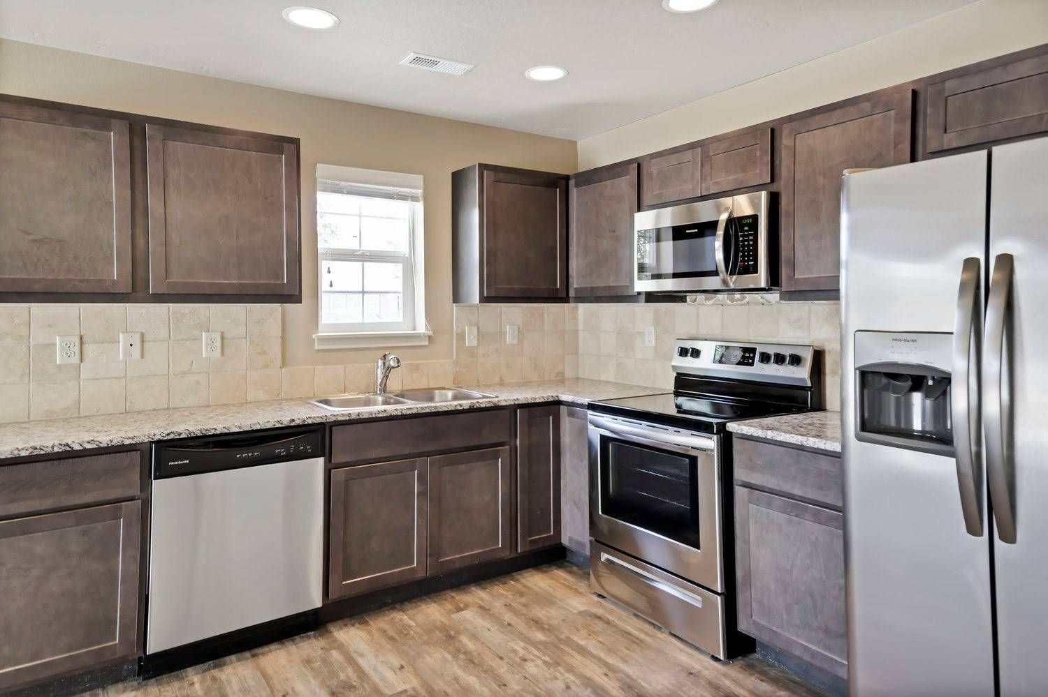 Modern kitchen with stainless steel appliances, granite countertops, and dark brown cabinets.