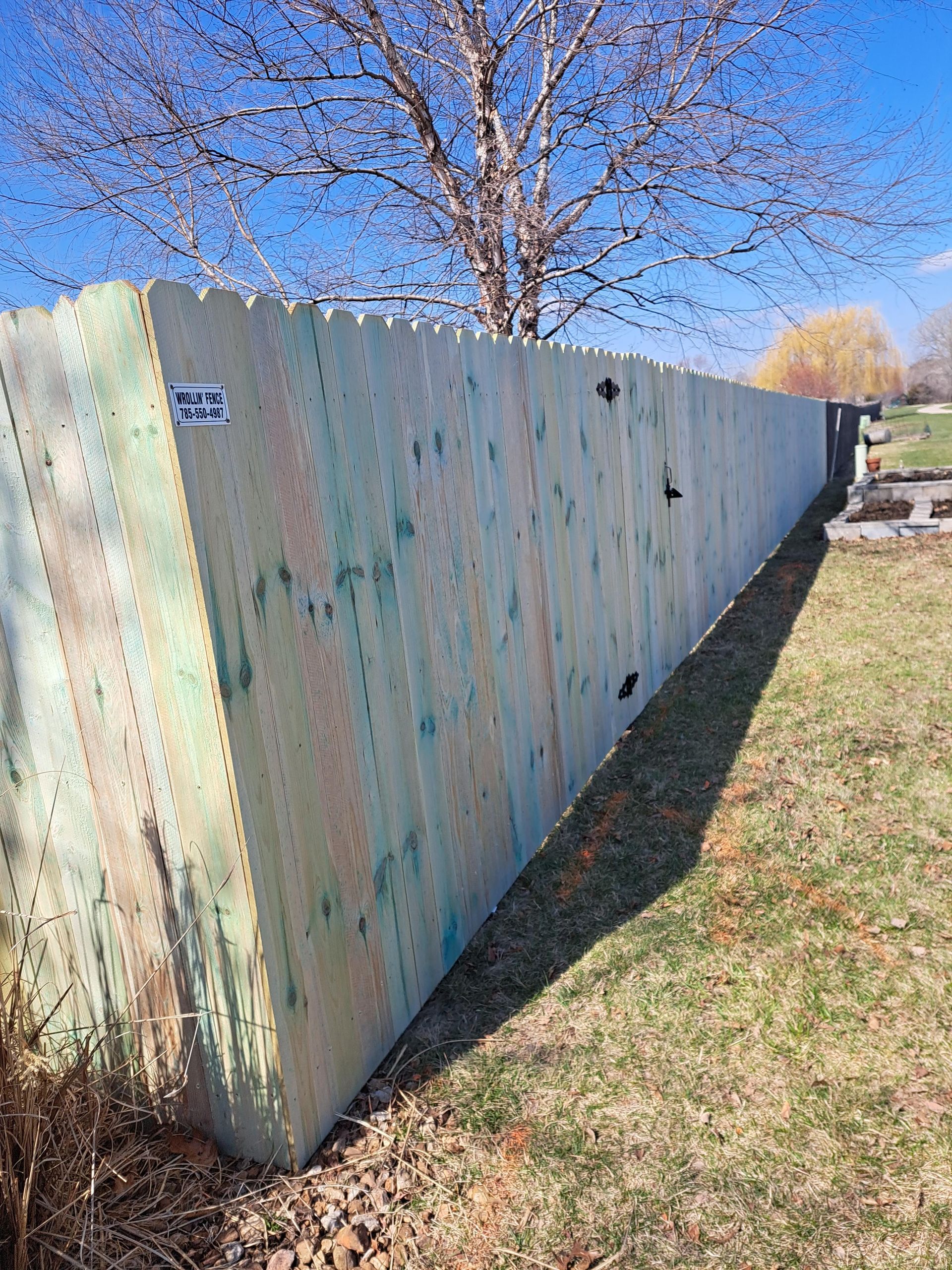 A long wooden fence is sitting in the middle of a grassy field.
