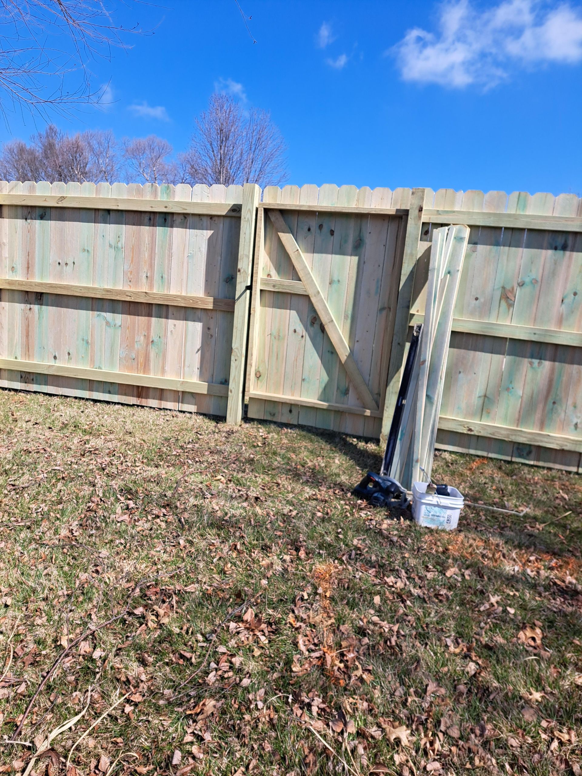 A wooden fence with a gate is sitting in the middle of a grassy field.