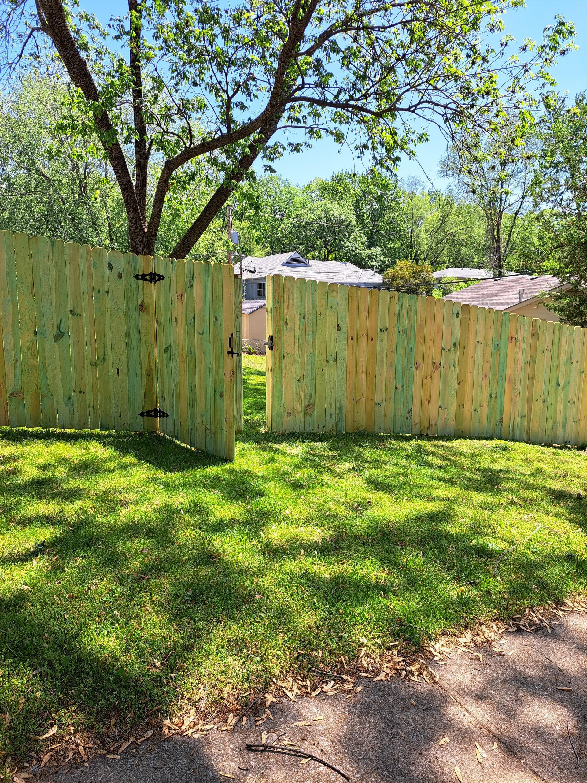 A wooden fence is in the middle of a lush green yard.