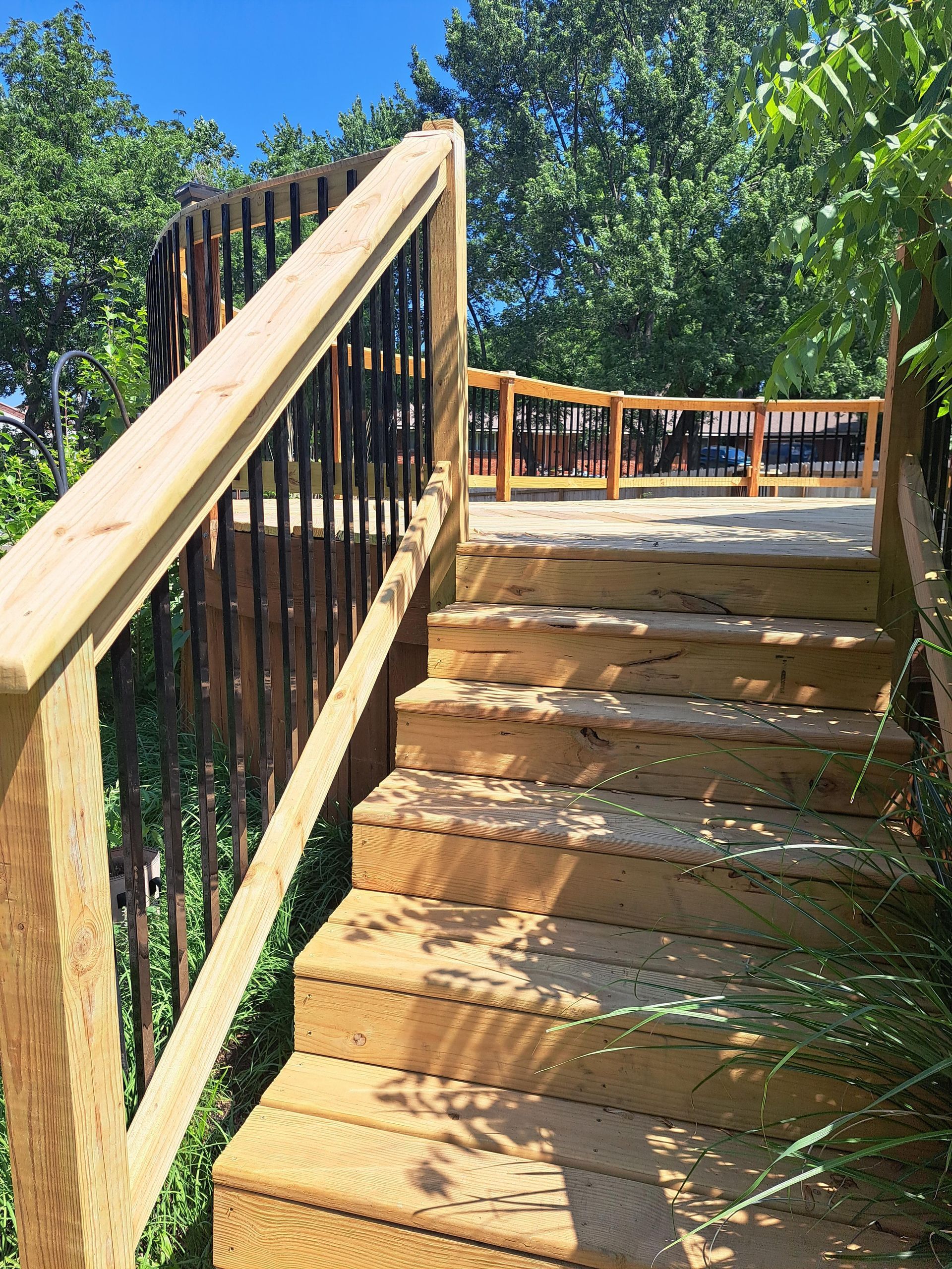 A wooden staircase leading up to a deck with a metal railing.