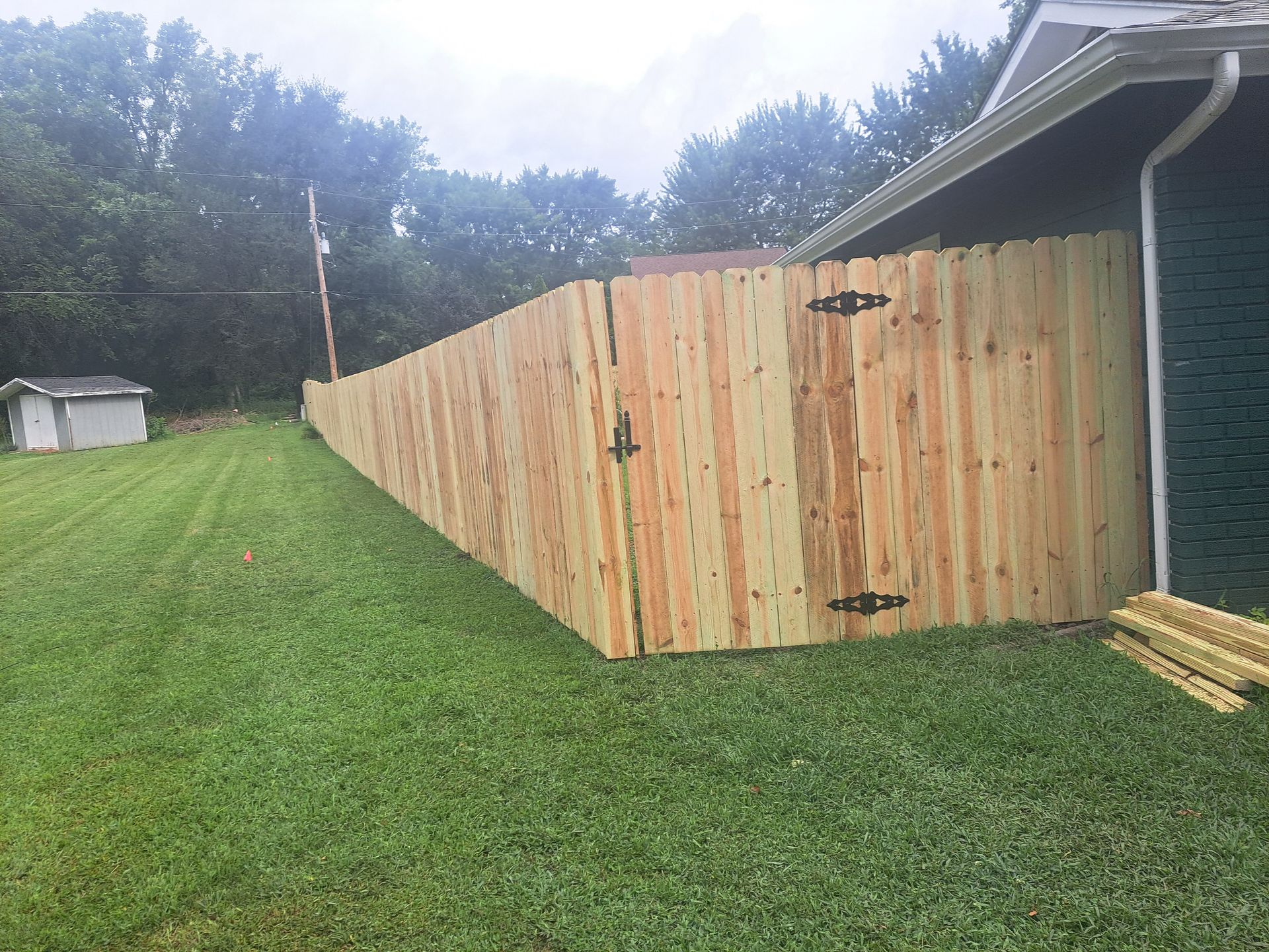 A wooden fence with a gate in the backyard of a house.