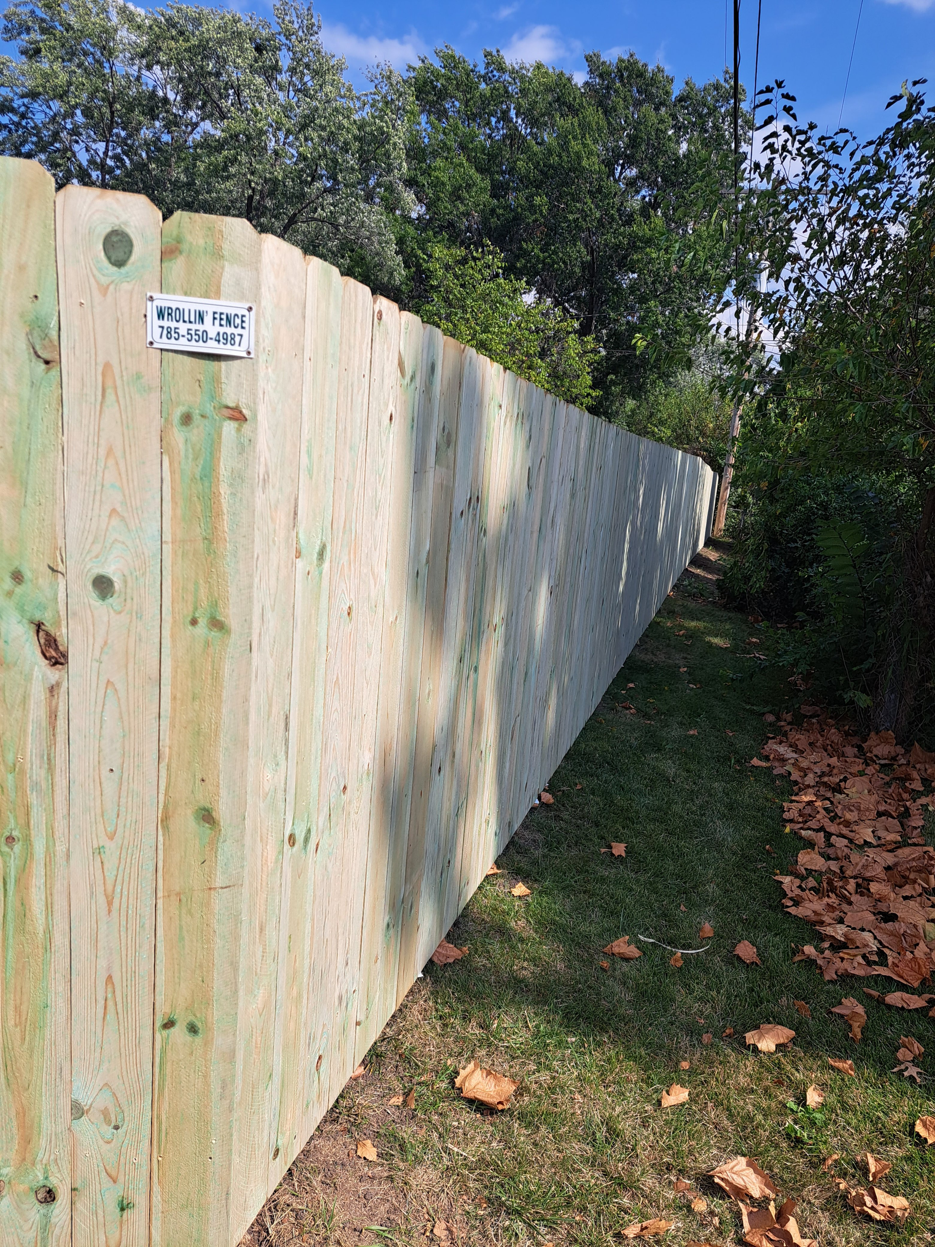 A wooden fence is sitting on top of a lush green field.