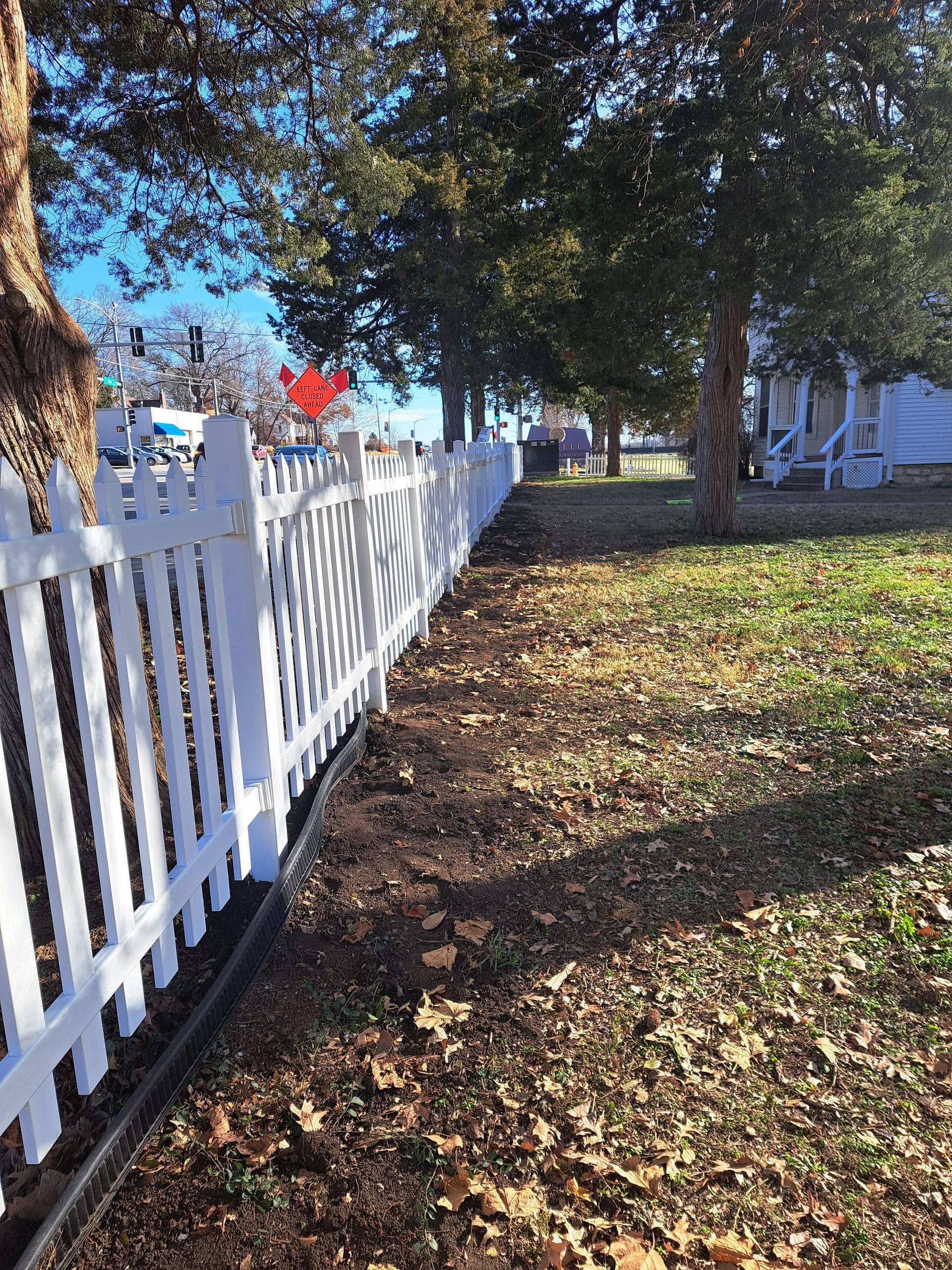 A white picket fence surrounds a lush green yard.