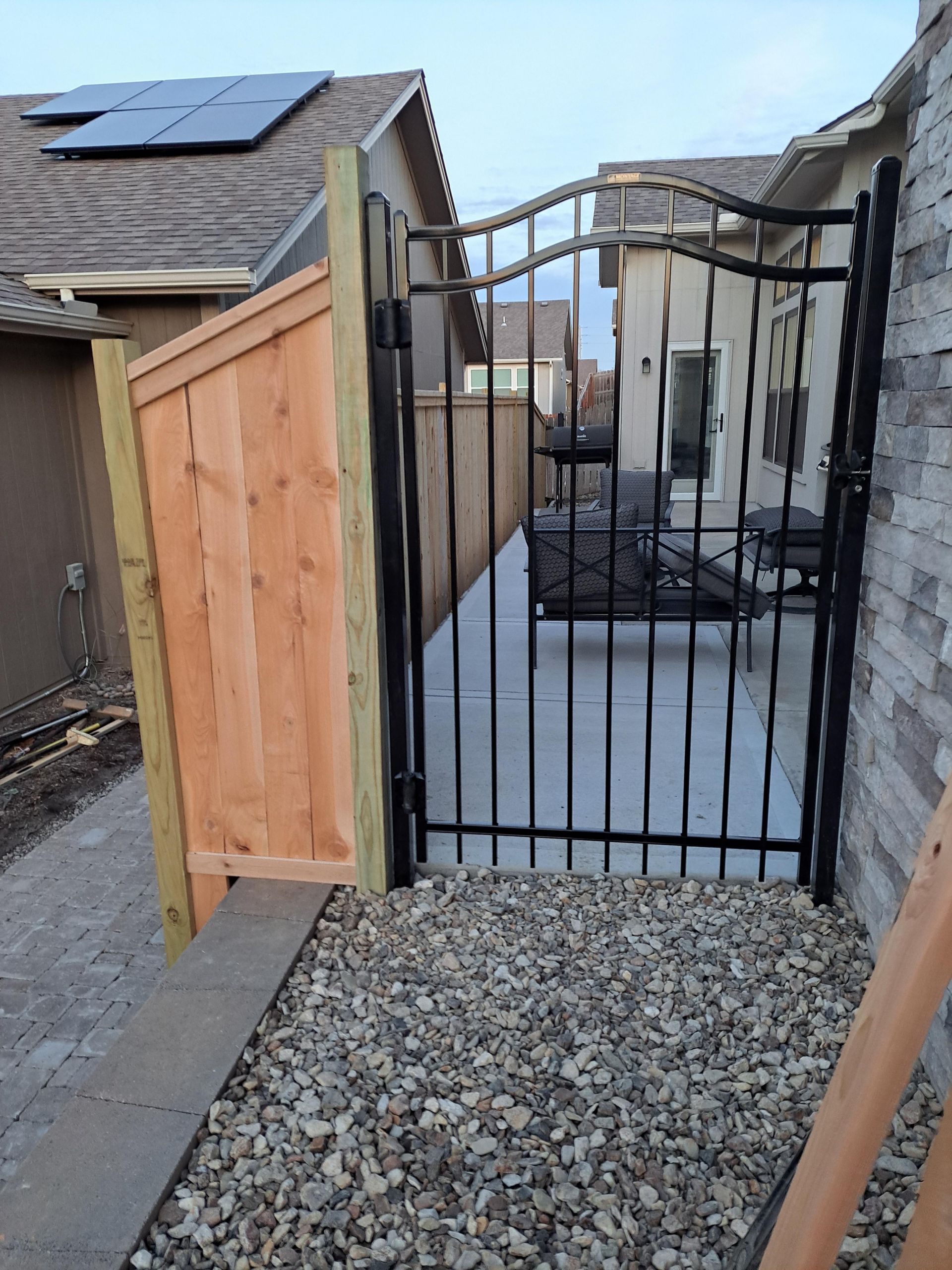 A wooden fence with a metal gate leading to a patio