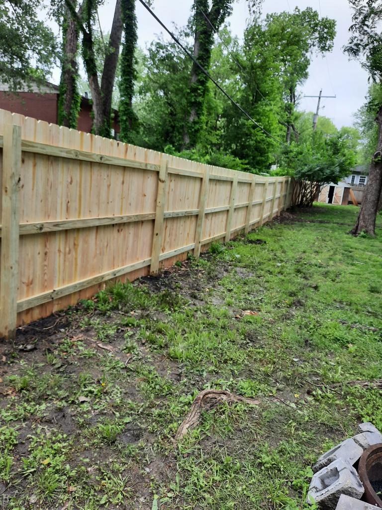 A wooden fence is sitting in the middle of a grassy yard.