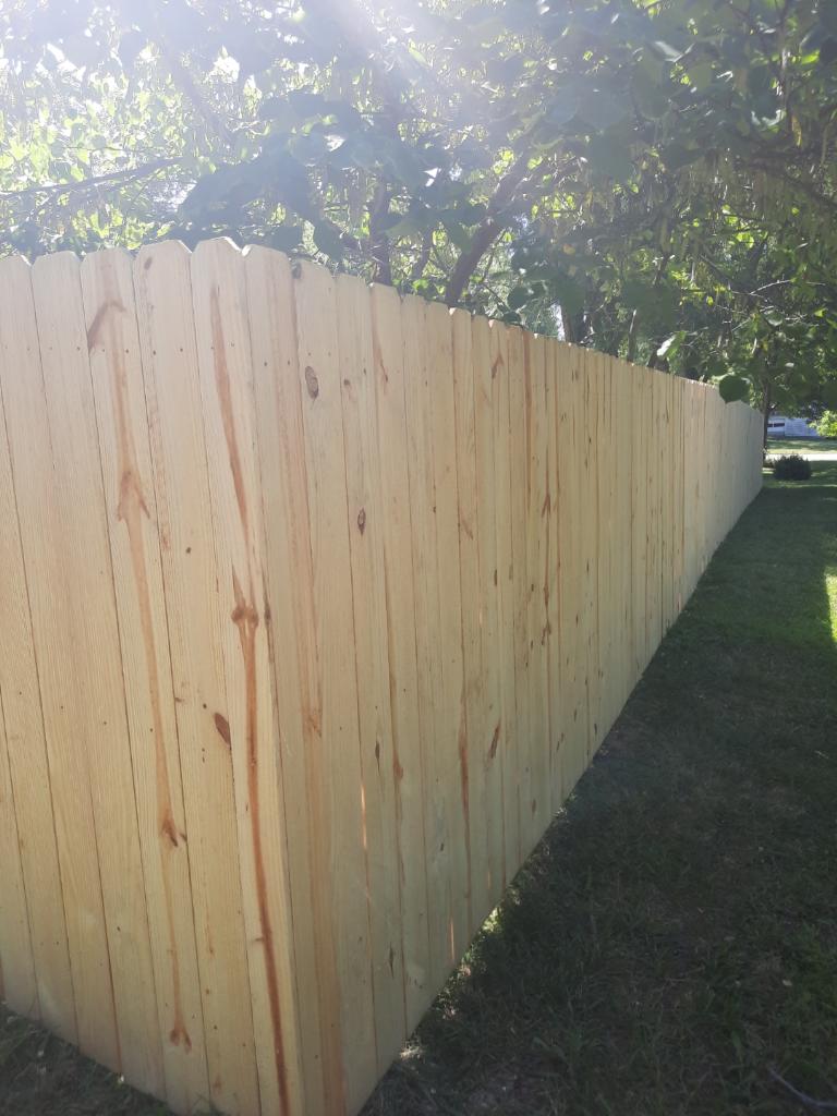 A wooden fence is sitting in the middle of a lush green field.