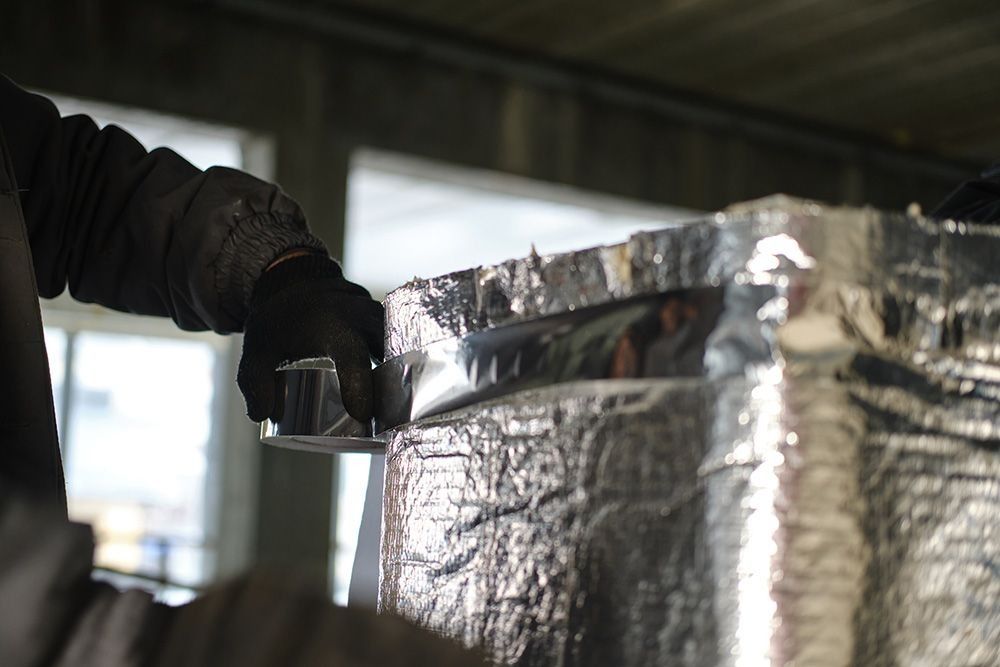 Person in Black Gloves Installing Shiny Silver Insulation — Climate King In Orange, NSW