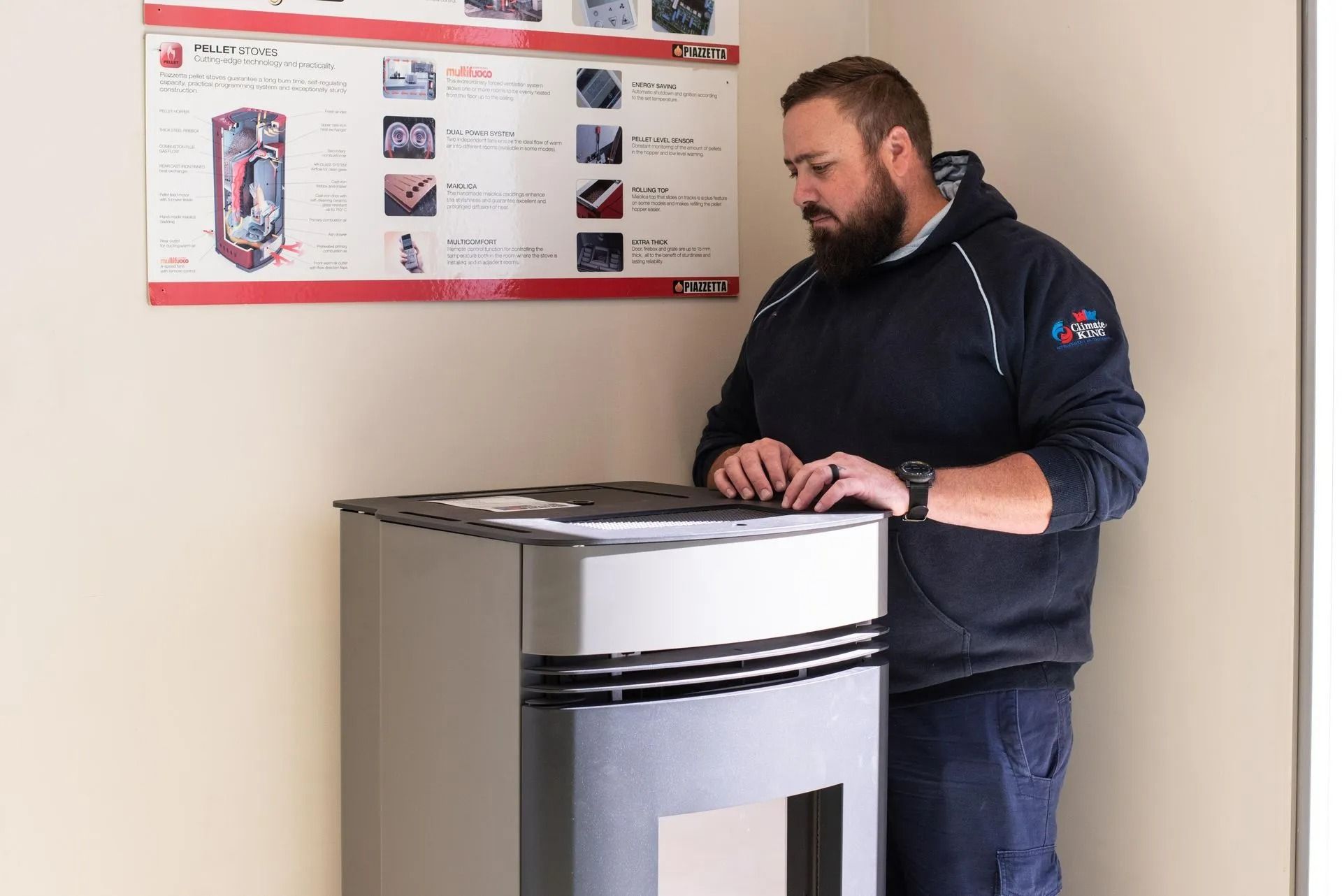 Man in Blue Hoodie Inspecting a Silver Pellet Stove — Climate King In Orange, NSW