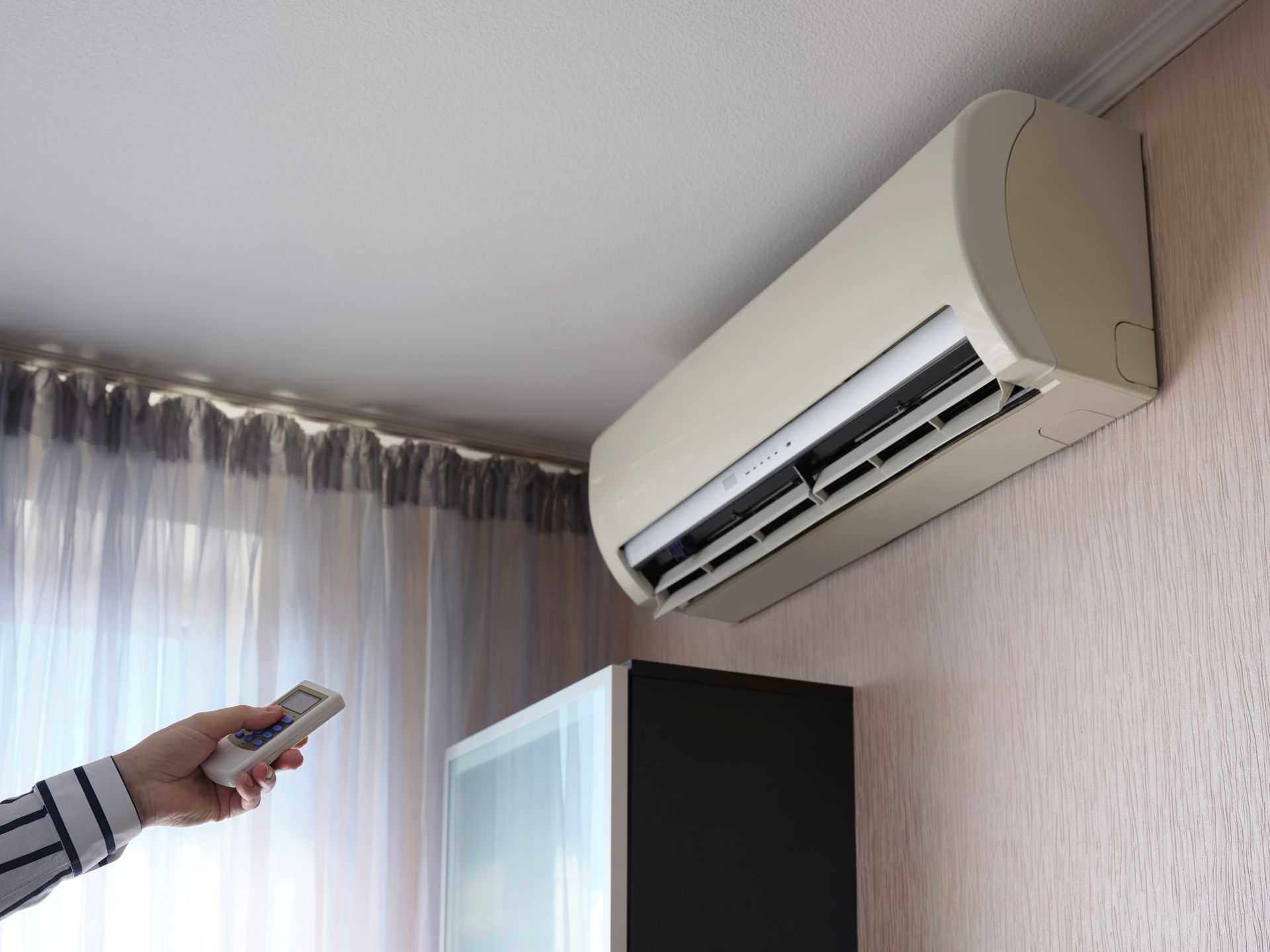 Person Using Remote to Control Wall-mounted Air Conditioner — Climate King In Orange, NSW