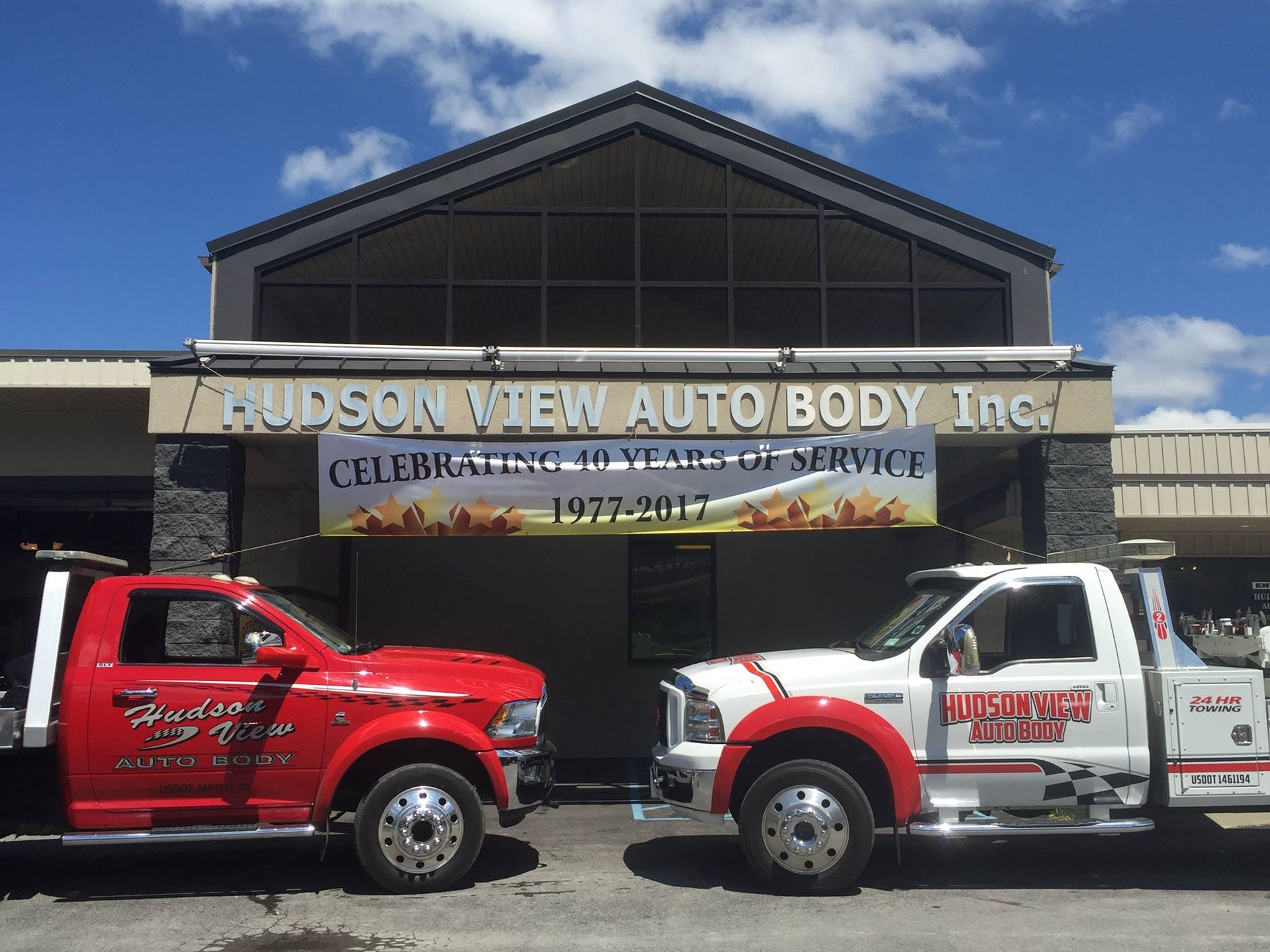 Two trucks are parked in front of a building that says hudson view auto body inc.