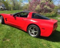 A red corvette is parked in a grassy field.