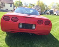 A red corvette is parked in a grassy field.