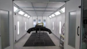A car is being painted in a paint booth.