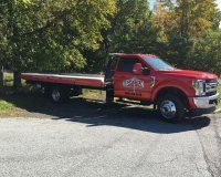 A red tow truck is parked on the side of the road.