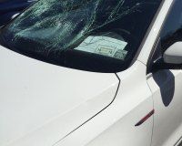 A close up of a white car with a broken windshield.
