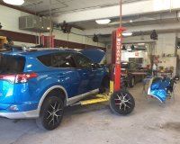 A blue car is sitting on a lift in a garage.