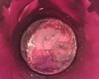 A close up of a pink glass with bubbles in it.