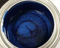 A can of blue paint is sitting on a table.