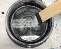 A bowl of liquid with a wooden stick in it.