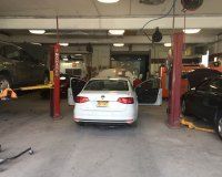 A white car is sitting on a lift in a garage.