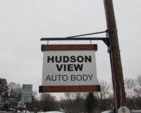 A sign for hudson view auto body is hanging from a pole.
