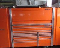 A large orange toolbox is sitting on top of a table.