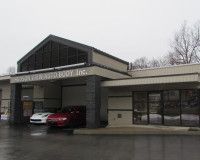 A building with cars parked in front of it on a rainy day.