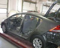 A car is sitting on a lift in a garage with the trunk open.