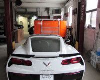 A white corvette is parked on a lift in a garage.