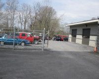 A lot of cars are parked in a parking lot behind a fence.