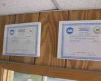 Two certificates are hanging on a wooden wall.