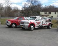 Two tow trucks are parked next to each other in a parking lot.