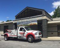 A white and red tow truck is parked in front of a building.