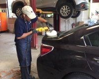 A man is polishing a car in a garage.