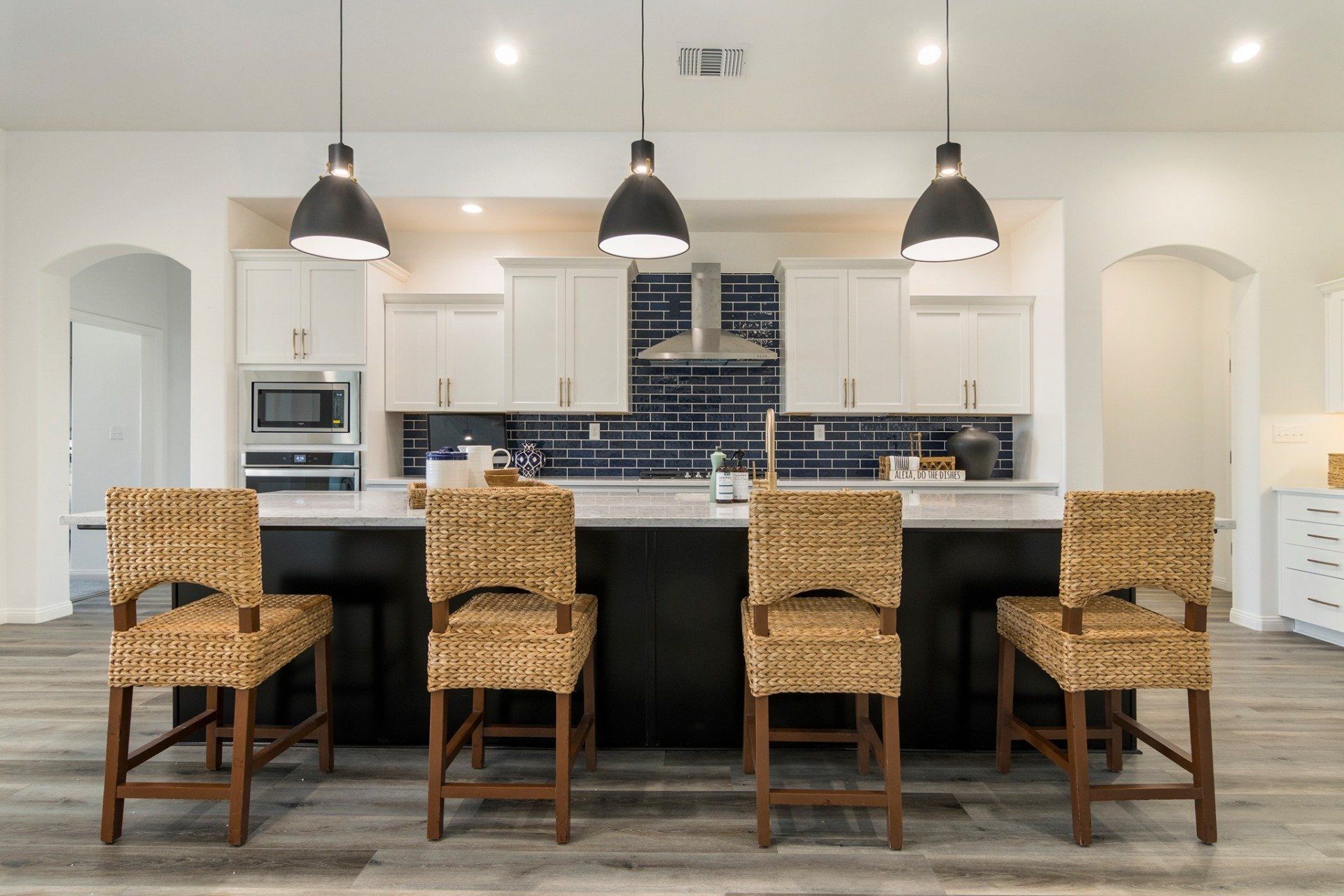A kitchen with a large island and wicker chairs
