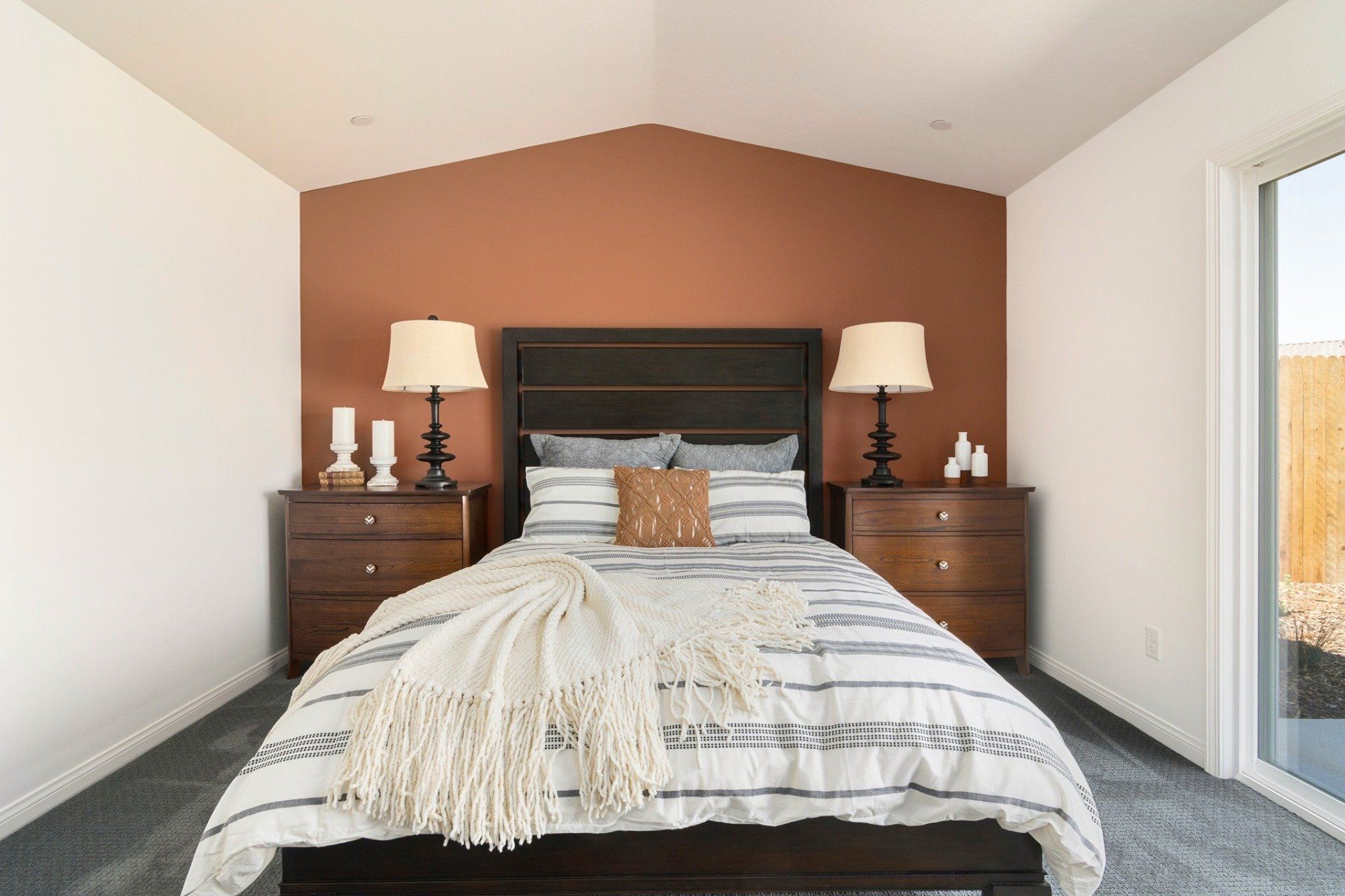 A bedroom with a bed , nightstands , lamps and a sliding glass door.