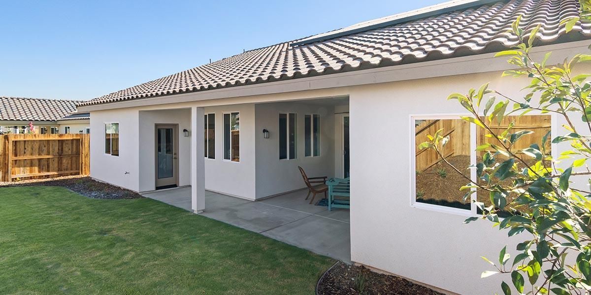 A white house with a tiled roof and a patio in the backyard.