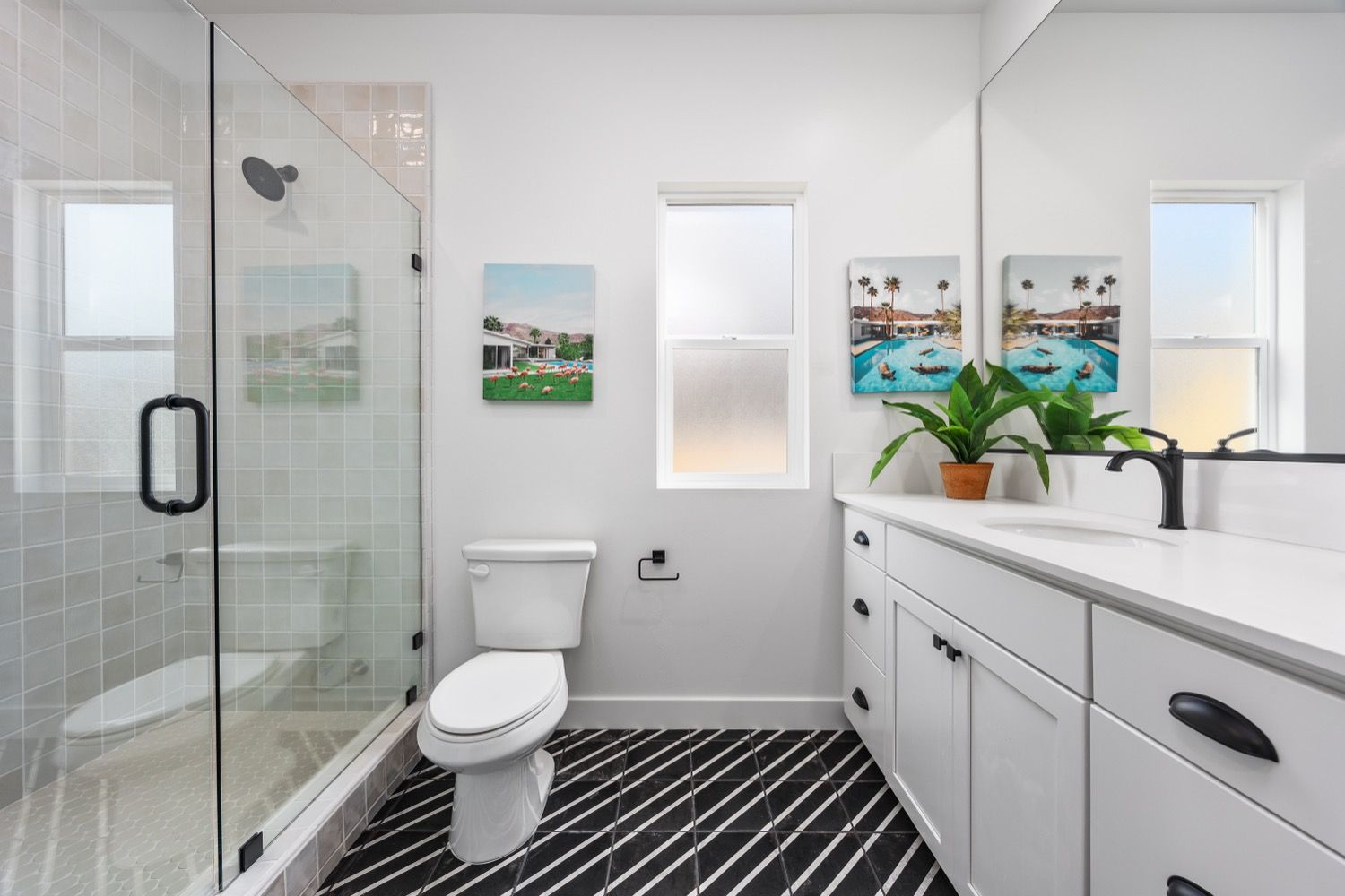 Modern bathroom with white walls, black and white striped floor, glass shower, and white vanity.