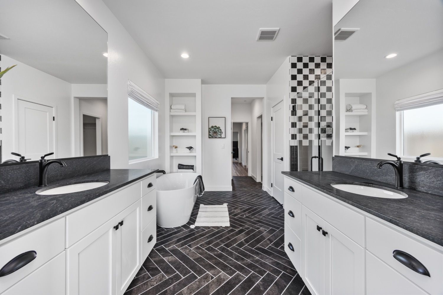 Modern bathroom with black and white tile design, double vanity, and freestanding tub.